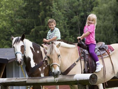 Familienhotel - Spielplatz - Allgäu - Kinder reiten auf Pferde - Ferienclub Maierhöfen