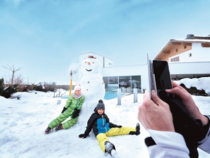 Familienhotel - Pools: Innenpool - Österreich - Spaß im Schnee auf der Hotelterrasse - Familotel amiamo