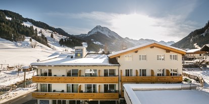 Familienhotel - Spielplatz - Großarl - Außenansicht im Winter mit Skipiste im Hintergrund - Familienhotel Botenwirt ***S