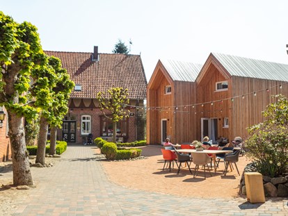 Familienhotel - Ladestation Elektroauto - Innenhof mit den Cabins und dem Bauernhaus - Familotel Landhaus Averbeck