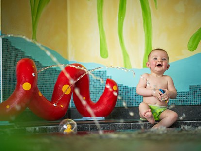 Familienhotel - Schwimmkurse im Hotel - Kössen - beheizter Babypool mit lustiger Spritzschlange und vielen Wasserspielsachen - Familotel amiamo