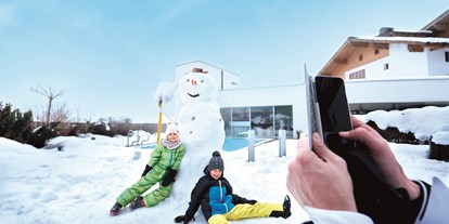 Familienhotel - Teenager-Programm - Salzburg - Spaß im Schnee auf der Hotelterrasse - Familotel amiamo