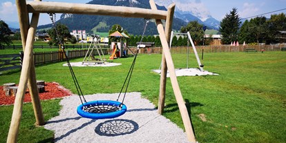 Familienhotel - Hunde verboten - Tirol - Freie Benützung der unmittelbar angrenzenden Spielwiese mit Nestschaukel, Seilrutsche, Spielturm und Trampolin - Hotel babymio