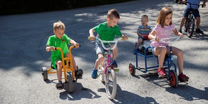 Familienhotel - Skilift - Tretfahrzeuge, Kinderfahrräder und Bobbycars vorm Hotel - Habachklause Familien Bauernhof Resort