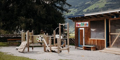 Familienhotel - Garten - Pinzgau - Spielplatz mit überdachter XXL-Sandkiste - Habachklause Familien Bauernhof Resort