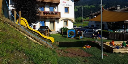 Familienhotel - Umgebungsschwerpunkt: Berg - Spielplatz zwischen Terrasse und Haus Antonia (Nebengebäude mit Appartements) - Hotel Felsenhof