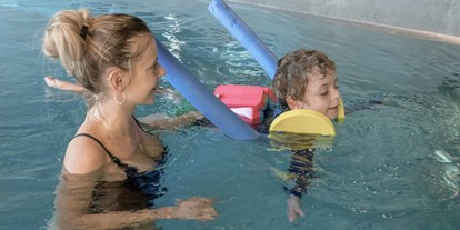 Familienhotel - ausschließlich Familien im Hotel - Unsere zertifizierten Schwimmtrainer:innen üben mit den kleinen die ersten koordinierten Bewegungen im Wasser - ganz entspannt - Gorfion Familotel Liechtenstein