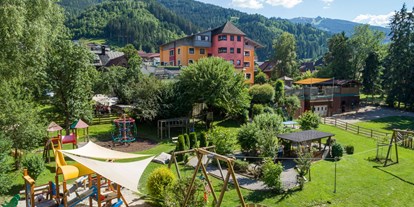Familienhotel - Verpflegung: Halbpension - Steiermark - Das großzügige Hotelareal mit rund herum abgesicherterm Spielplatz und vielen schattenspendenden Bäumen  - Bliems Familienhotel**** Schladming