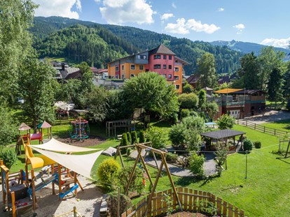 Familienhotel - Umgebungsschwerpunkt: Berg - Schladming-Dachstein - Das großzügige Hotelareal mit rund herum abgesicherterm Spielplatz und vielen schattenspendenden Bäumen  - Bliems Familienhotel**** Schladming