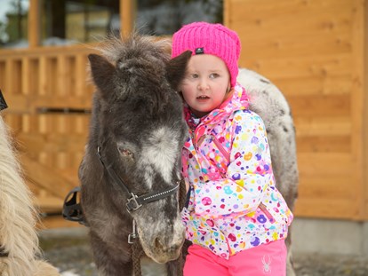Familienhotel - Ponyreiten - Mädchen kuschelt mit dem Pony - Familienhotel Auhof