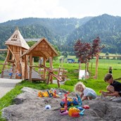 Familienhotel: Spielplatz mit Klettermöglichkeit, Rutsche, Sandkasten, Wasserpumpe, Dreiradrange, Schaukel,.... - ****Alpen Hotel Post