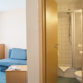 Kinderhotel: Familien-Studio - Wohnbereich mit Schlafcouch für Kinder und Dusche / WC - Werrapark Resort Hotel Heubacher Höhe