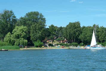Kinderhotel: Badestrand mit Buddelsand und Liegewiese und Seebrücke mit kleinem Hafen ( Boote im Verleih ) - Aparthotel Am See