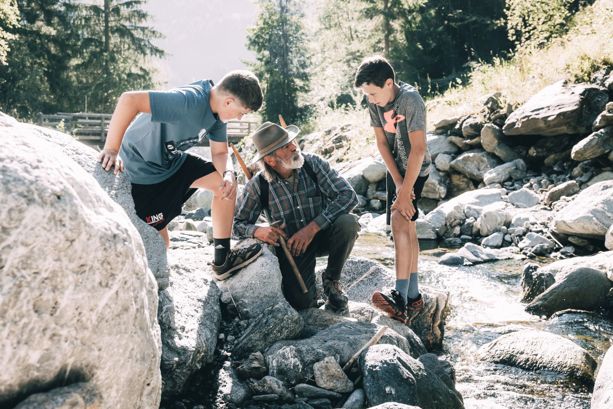 Kinder spielen am Bach und suchen Steine im Kinderhotel Stegerhof in der Steiermark.