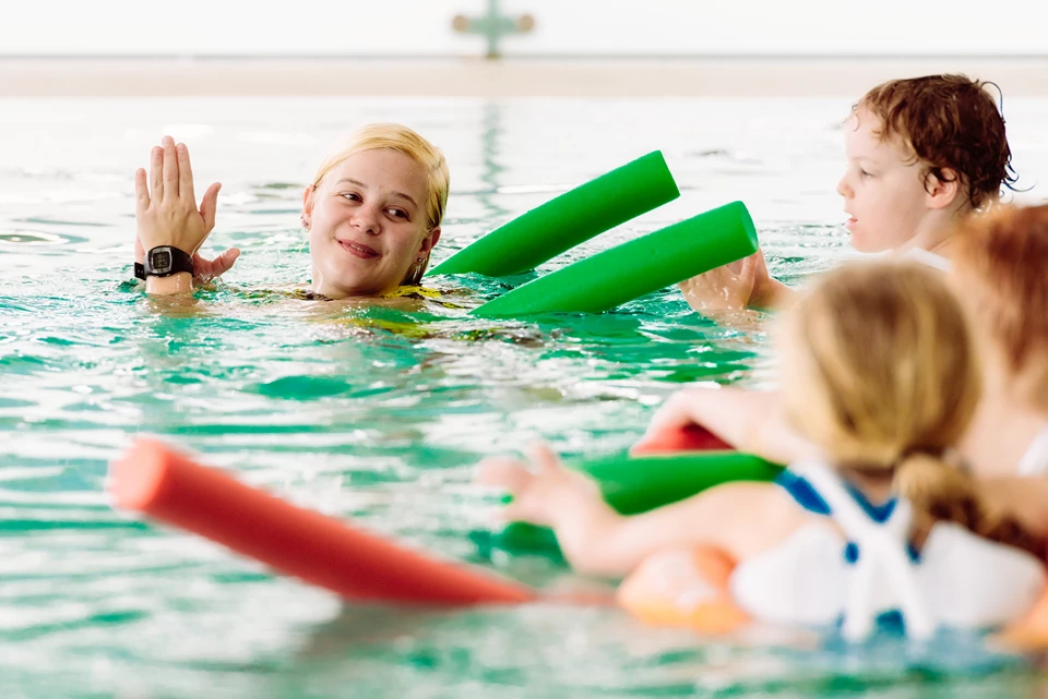 Kinder und Schwimmlehrerin beim Schwimmkurs im Familienhotel