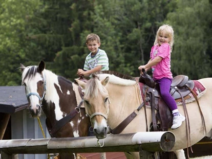 Familienhotel - Spielplatz - Kinder reiten auf Pferde - Ferienclub Maierhöfen