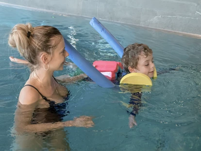 Familienhotel - Kinderbetreuung - Flims Waldhaus - Unsere zertifizierten Schwimmtrainer:innen üben mit den kleinen die ersten koordinierten Bewegungen im Wasser - ganz entspannt - Gorfion Familotel Liechtenstein