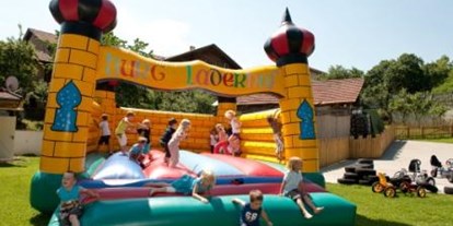 Familienhotel - WLAN - PLZ 6993 (Österreich) - Auf dem Spielplatz toben sich die Kinder in der Hüpfburg aus - Kinderhotel Laderhof
