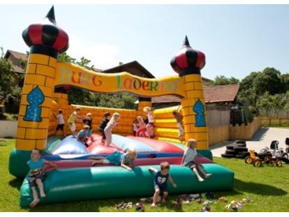 Familienhotel - Pools: Innenpool - Auf dem Spielplatz toben sich die Kinder in der Hüpfburg aus - Kinderhotel Laderhof