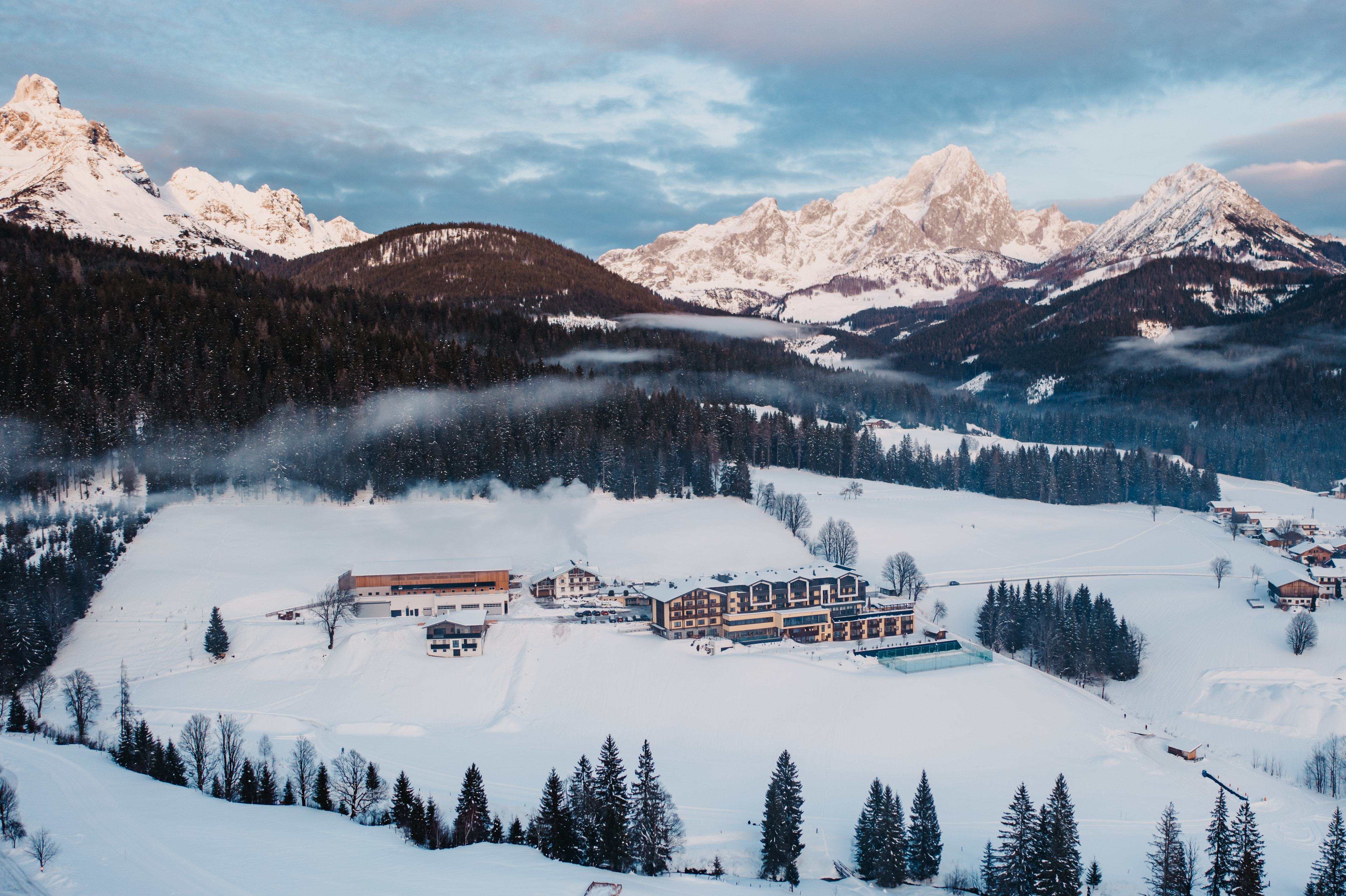 Kinderhotel - Eingebettet in eine idyllische Winterlandschaft liegt der Hotel Neubergerhof umgeben von verschneiten Wiesen und dichten Wäldern. Im Hintergrund erheben sich majestätisch die Gipfel des Dachstein, die in der klaren Bergluft strahlen. Die ruhige, unberührte Natur rund um das Hotel vermittelt ein Gefühl von Geborgenheit, Erholung und alpiner Weite – ein perfekter Ort für Winterurlaub und entspannte Tage in den Salzburger Bergen. - Hotel …mein Neubergerhof****