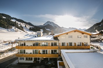 Familienhotel: Außenansicht im Winter mit Skipiste im Hintergrund - Familienhotel Botenwirt ***S
