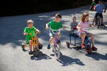 Kinderhotel: Tretfahrzeuge, Kinderfahrräder und Bobbycars vorm Hotel - Habachklause Familien Bauernhof Resort