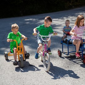 Kinderhotel: Tretfahrzeuge, Kinderfahrräder und Bobbycars vorm Hotel - Habachklause Familien Bauernhof Resort