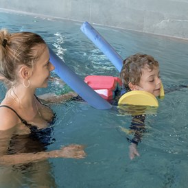 Kinderhotel: Unsere zertifizierten Schwimmtrainer:innen üben mit den kleinen die ersten koordinierten Bewegungen im Wasser - ganz entspannt - Gorfion Familotel Liechtenstein