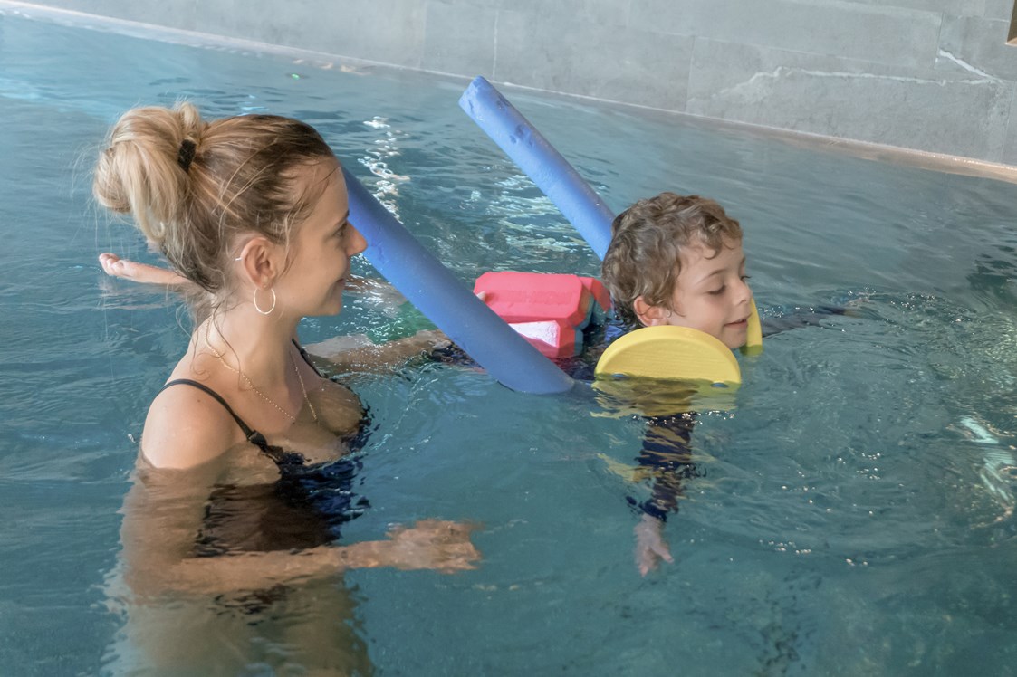Kinderhotel: Unsere zertifizierten Schwimmtrainer:innen üben mit den kleinen die ersten koordinierten Bewegungen im Wasser - ganz entspannt - Gorfion Familotel Liechtenstein