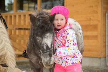 Familienhotel: Mädchen kuschelt mit dem Pony - Familienhotel Auhof