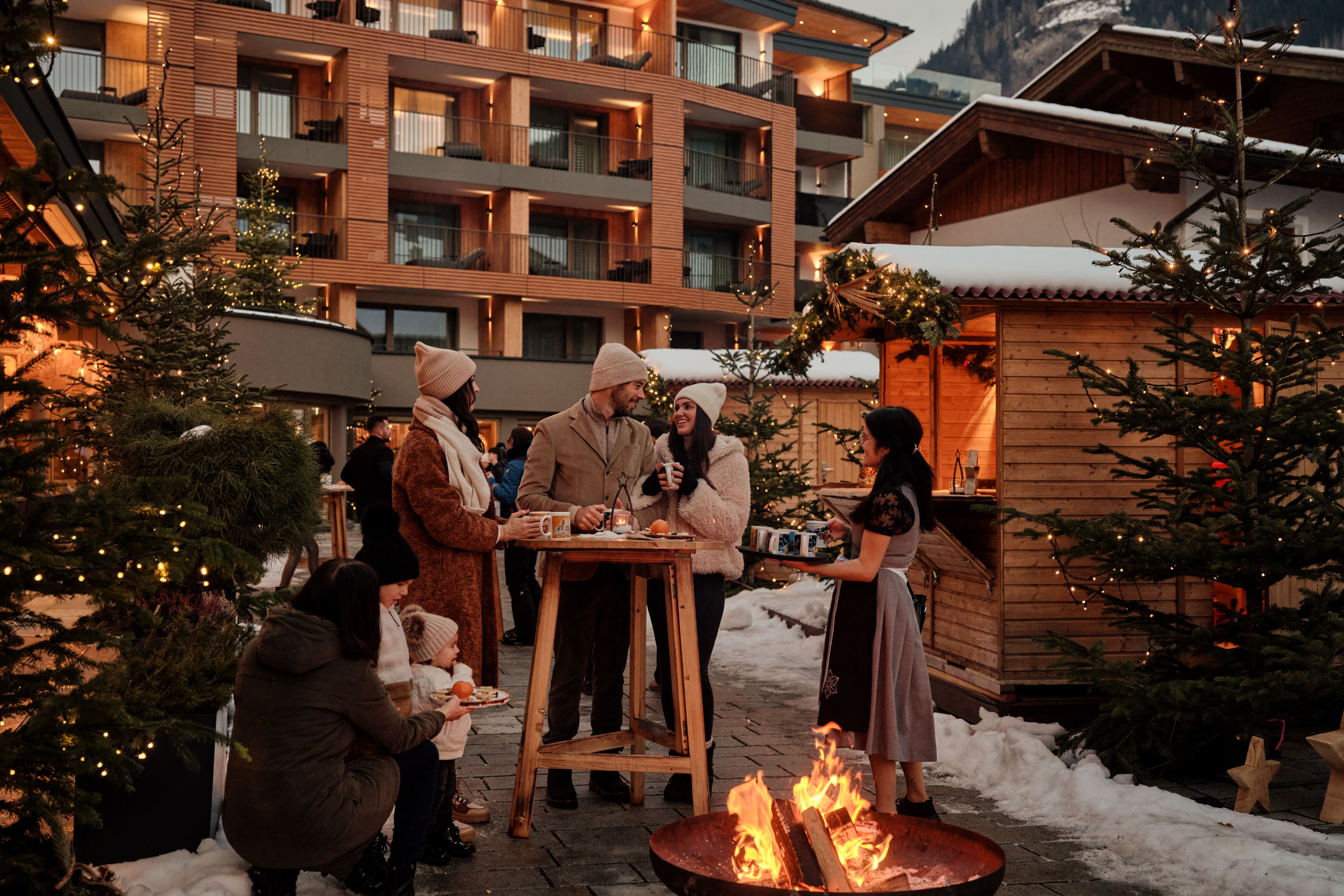 Kinderhotel: Stimmungsvoller Adventmarkt in der Outdoor-Lounge des DAS EDELWEISS Salzburg Mountain Resort in Großarl mit festlicher Beleuchtung und vorweihnachtlicher Atmosphäre. - DAS EDELWEISS Salzburg Mountain Resort