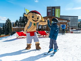 Kinderhotel: Maskottchen YOKI AHORN beim Skispass auf der Piste. - AHORN Hotel Am Fichtelberg