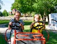 Kinderhotel: Kinder auf dem 4-Personen-Kettcar im großen Garten vom Bio Kinder- und Familienhotel Gut Nisdorf - Bio Kinder- & Familienhotel Gut Nisdorf
