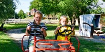 Familienhotel - Ostsee - Kinder auf dem 4-Personen-Kettcar im großen Garten vom Bio Kinder- und Familienhotel Gut Nisdorf - Gut Nisdorf - Bio Urlaub an der Ostsee